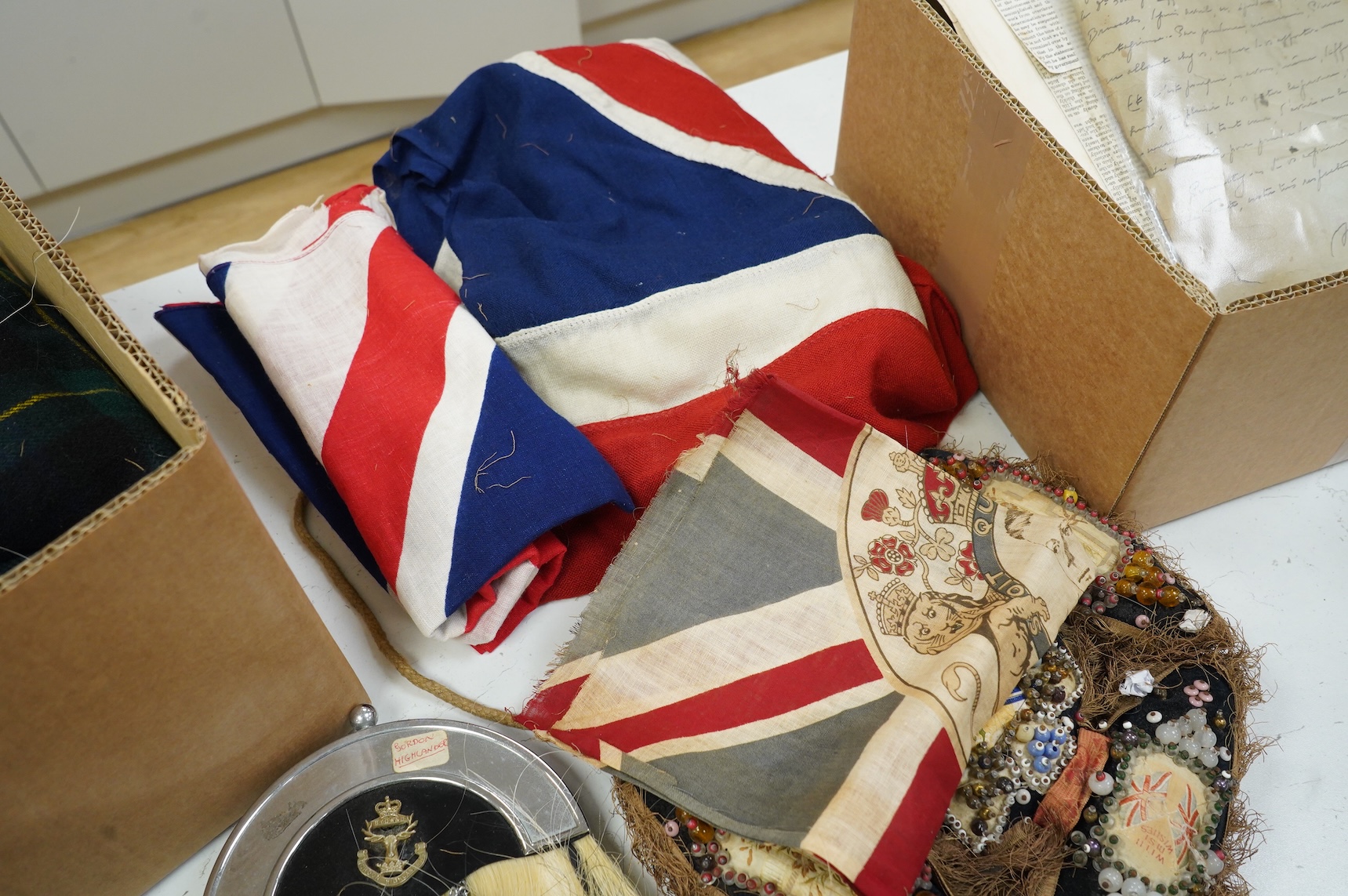 A collection of militaria, etc. including; a Gordon Highlander’s kilt and sporran, three early 20th century Union Flags, a Victorian beaded ‘sweetheart’s’ cushion, two empty First World War Princess Mary Christmas tins,